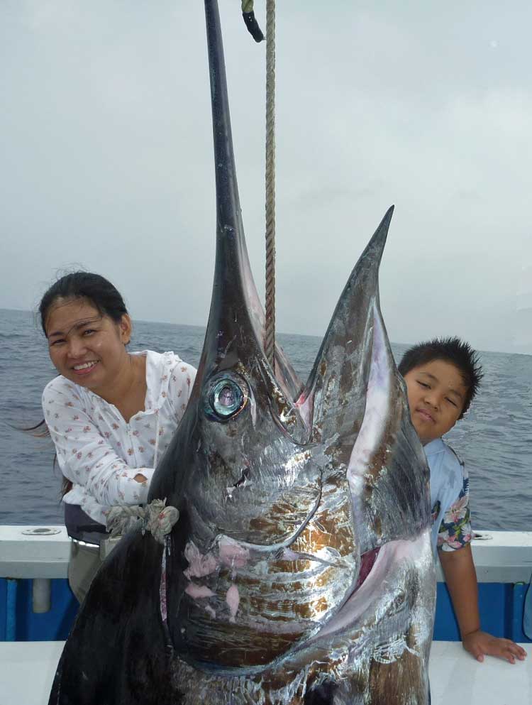 女性が180kgのカジキを釣り上げ子供と記念撮影2015年6月26日クレーンズ沖縄、鶴丸のトローリングにて船長は鶴巻守