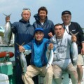 釣れた魚で記念撮影している５人の男