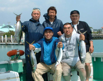 釣れた魚で記念撮影している５人の男