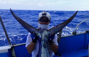 釣り上げたクロカジキの尾ビレとアングラー