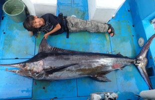 自力で釣り上げたカジキと横になっている少年