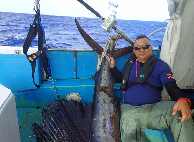 沖縄のトローリングで釣り上げたバショウカジキとアングラーの男性