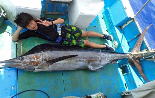自ら釣り上げたカジキと横になっている16才の高校生
