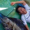 釣り上げたカジキと横に寝ている男