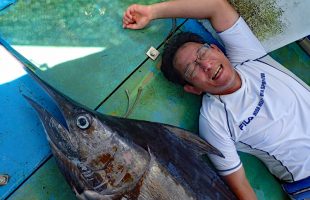 釣り上げたカジキと横に寝ている男