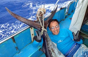 釣り上げたカジキとピースサインの男