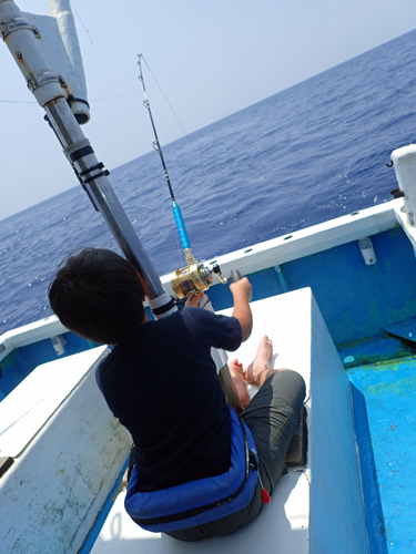 トローリングでマグロを釣っている少年の後ろ姿