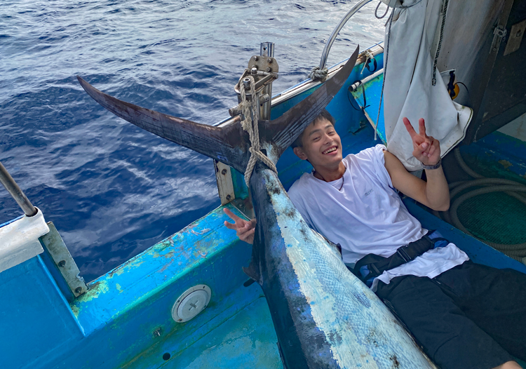 推定130kgのカジキを釣り上げピースサインをするた東京から沖縄に釣りに来た若い男性
