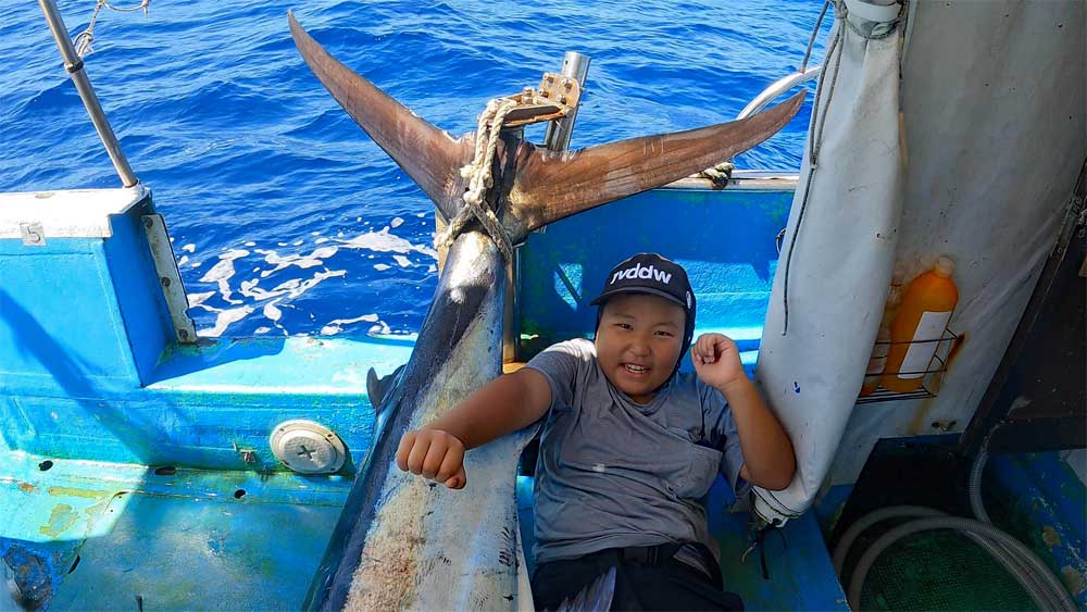 沖縄のトローリングで釣り上げたカジキと9才の小学生