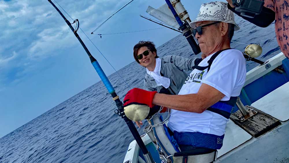 カジキを釣りをしている70才の男性と見守る息子