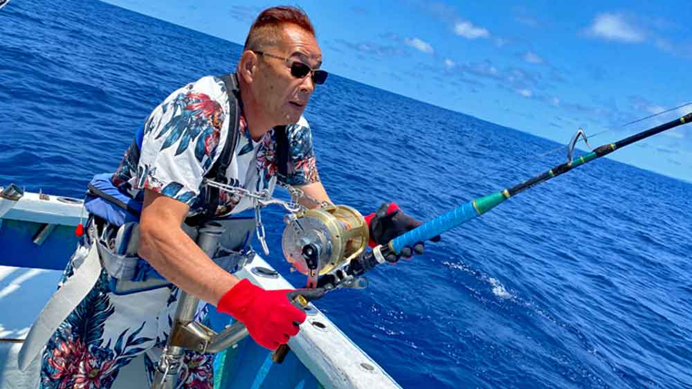 沖縄の海でカジキを釣っている男性