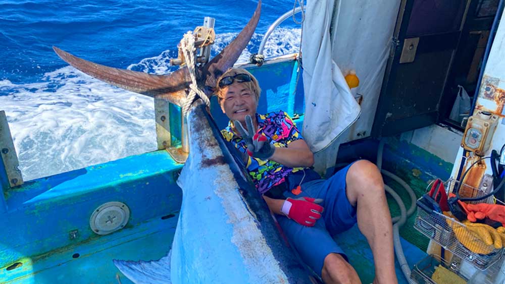 カジキを釣り上げピースサインの男性