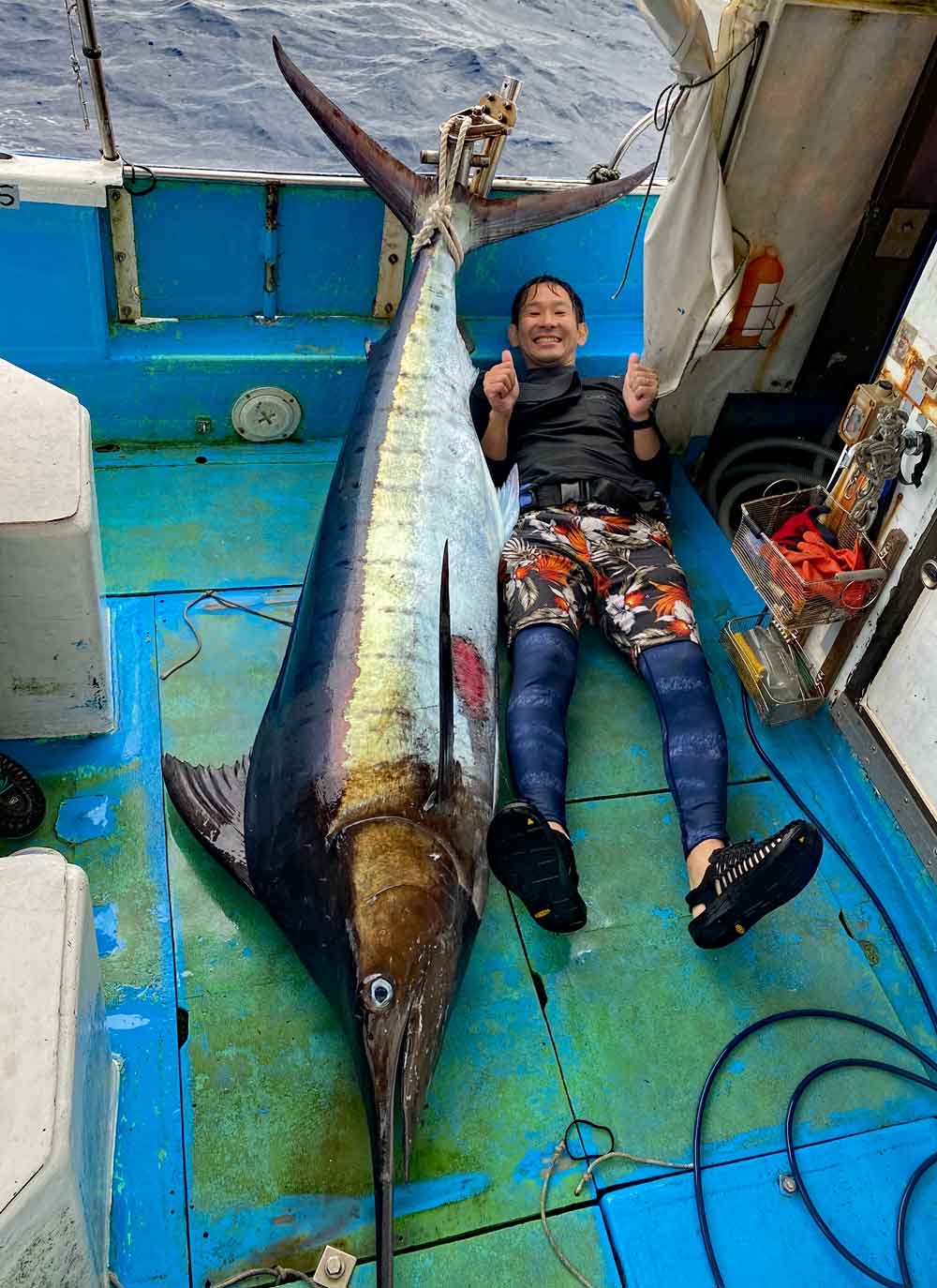 鶴丸のトローリングで釣り上げたカジキと男性