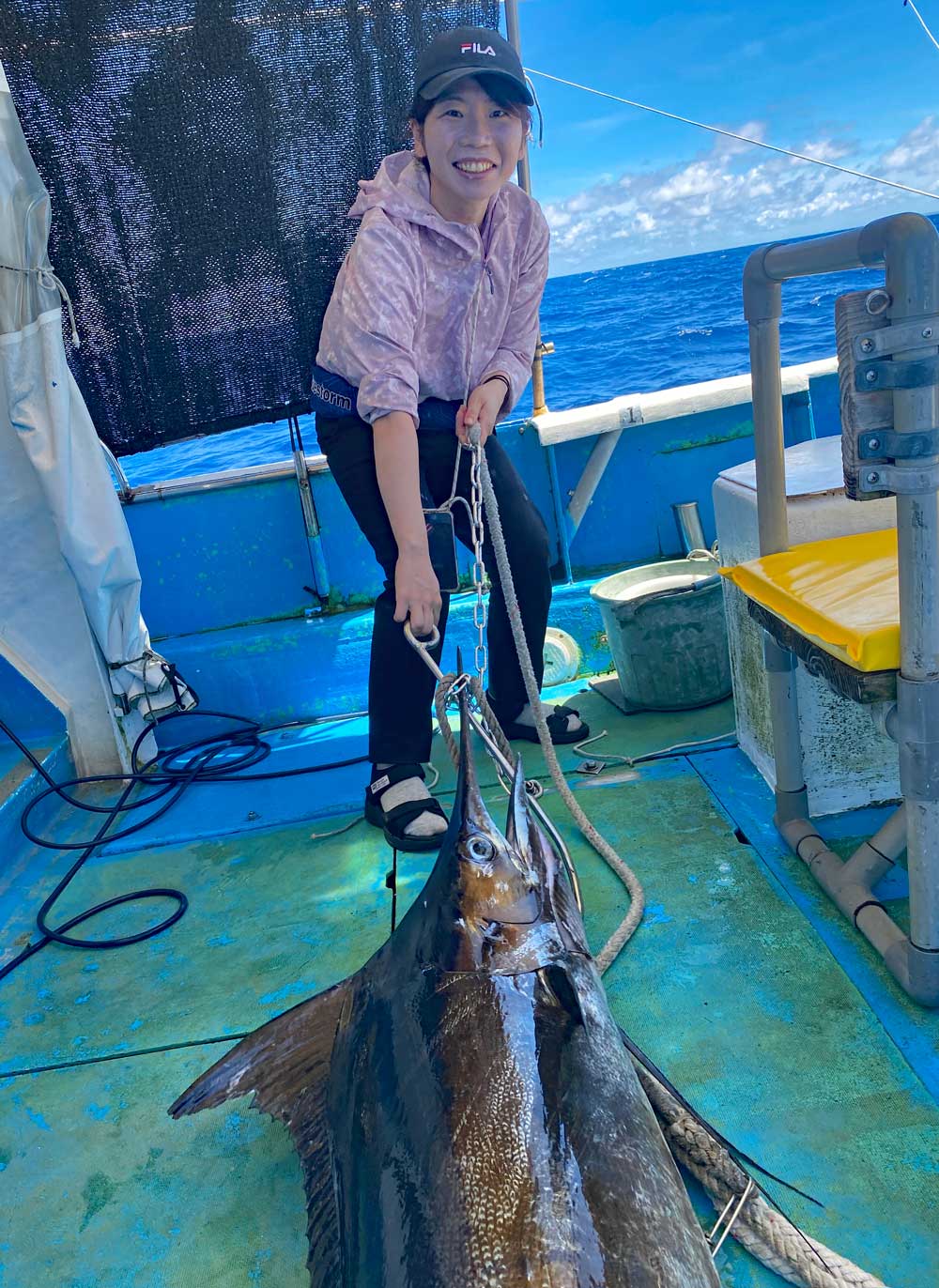 夫の釣ったカジキを船に引き上げた女性