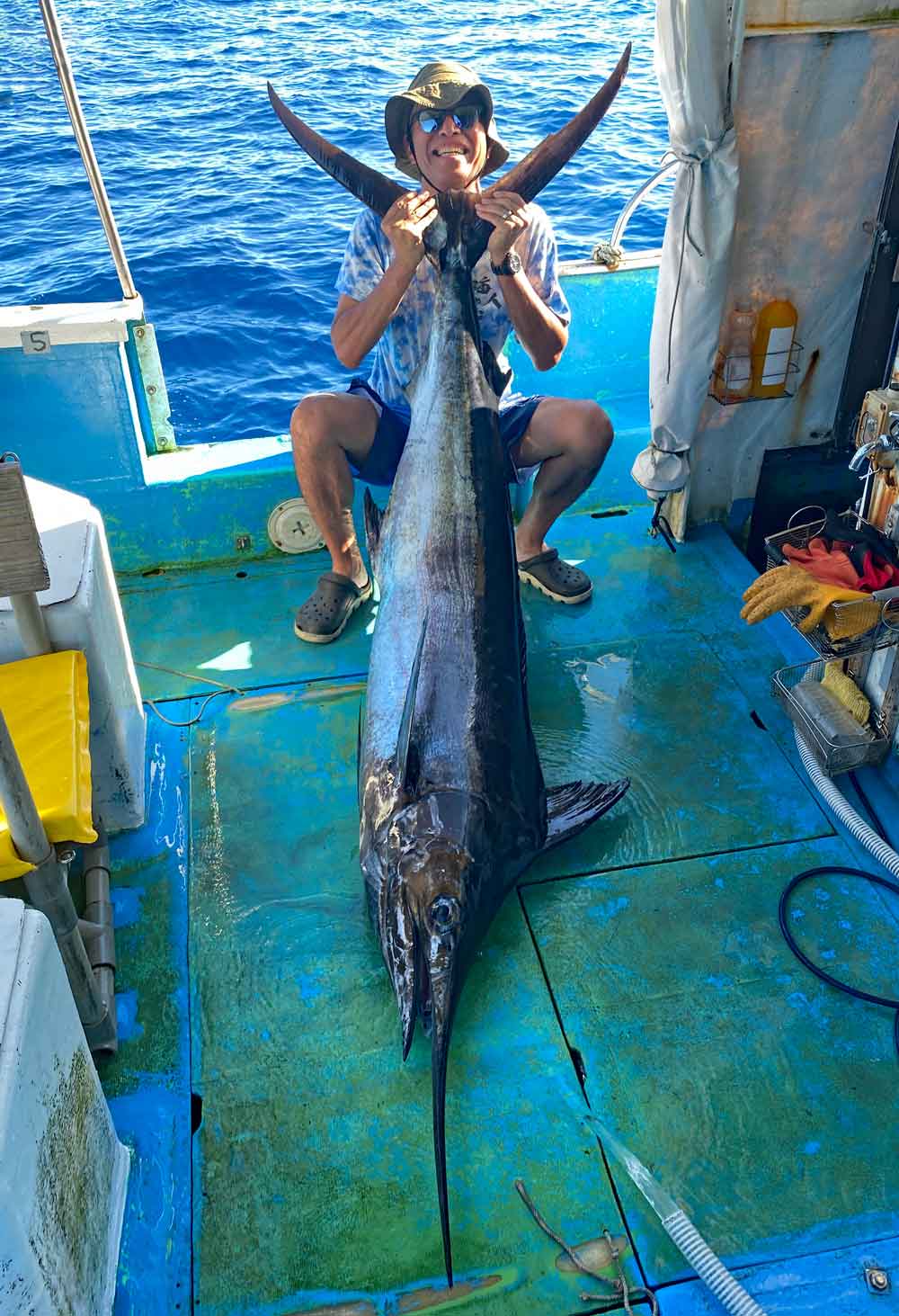 カジキを釣り上げ尾を持ち上げている男