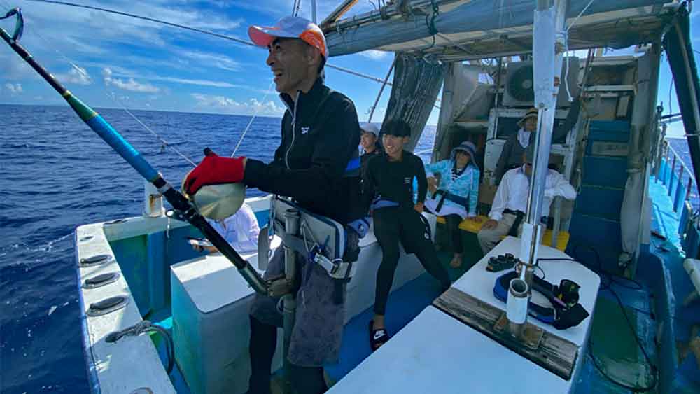 カジキ釣りをしている父と後ろで見守る家族