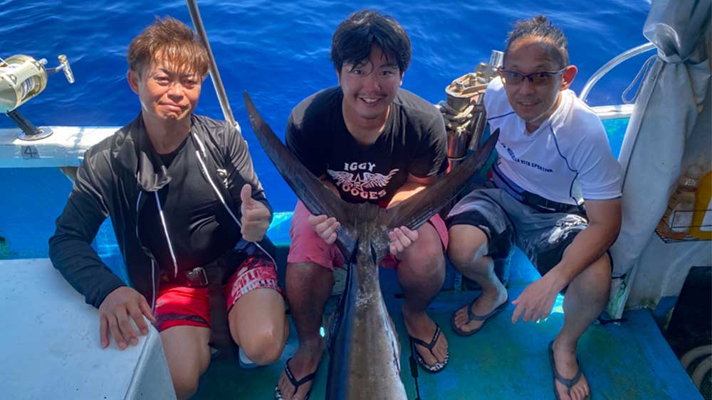 沖縄のトローリングで釣り上げたマカジキと三人の男性