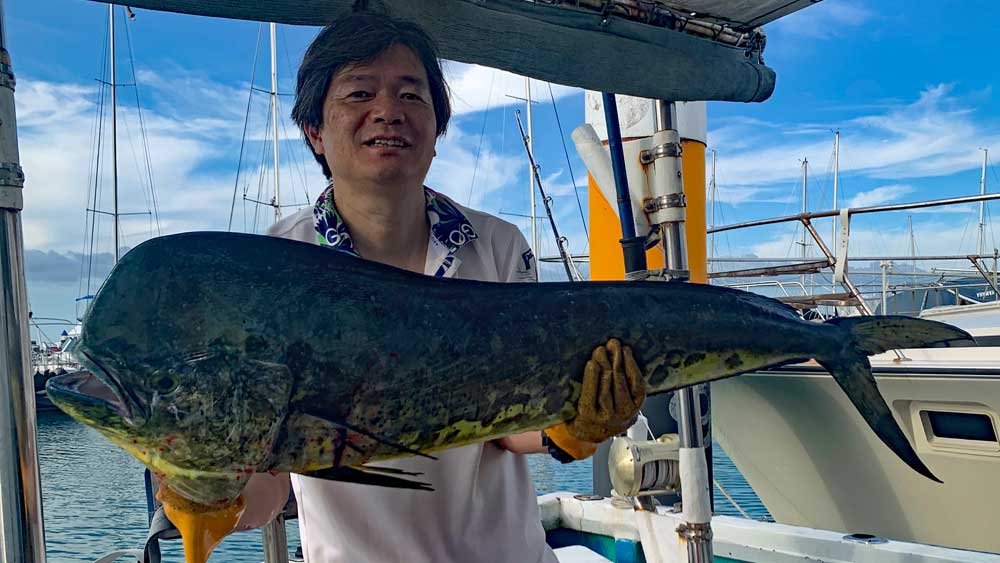 沖縄のトローリングで大物シイラを釣り上げた男性