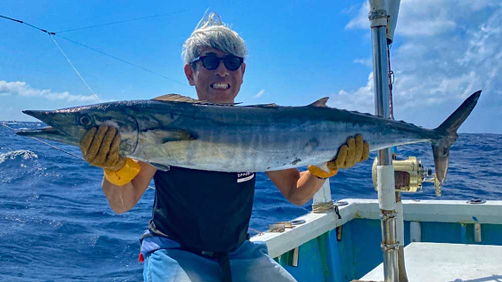 トローリングで大物カマスサワラを釣り上げたサングラスの男