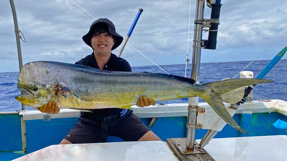 鶴丸のトローリングで大物シイラを釣り上げた帽子の男性