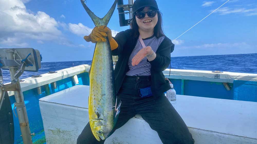 沖縄のトローリングでシイラを釣り上げ喜ぶ女性