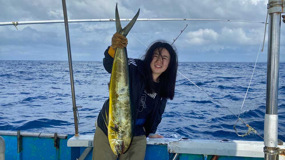 沖縄トローリングでシイラを釣り上げ喜ぶ中国の女性