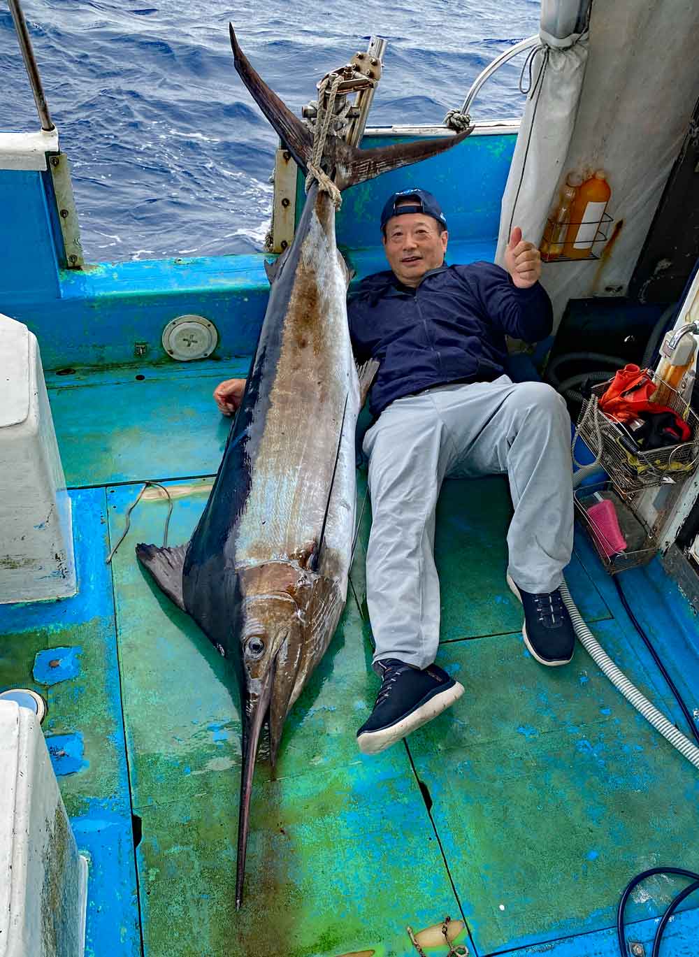 沖縄のトローリングでシロカジキ/Black Marlinを釣り上げ横になっている男性