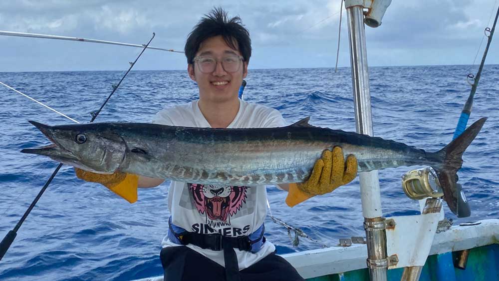 沖縄トローリングでサワラを釣り上げ喜ぶ中国の男性