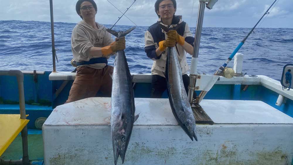 沖縄トローリングで2本のカマスサワラを釣り上げ喜ぶ二人の中国人男性