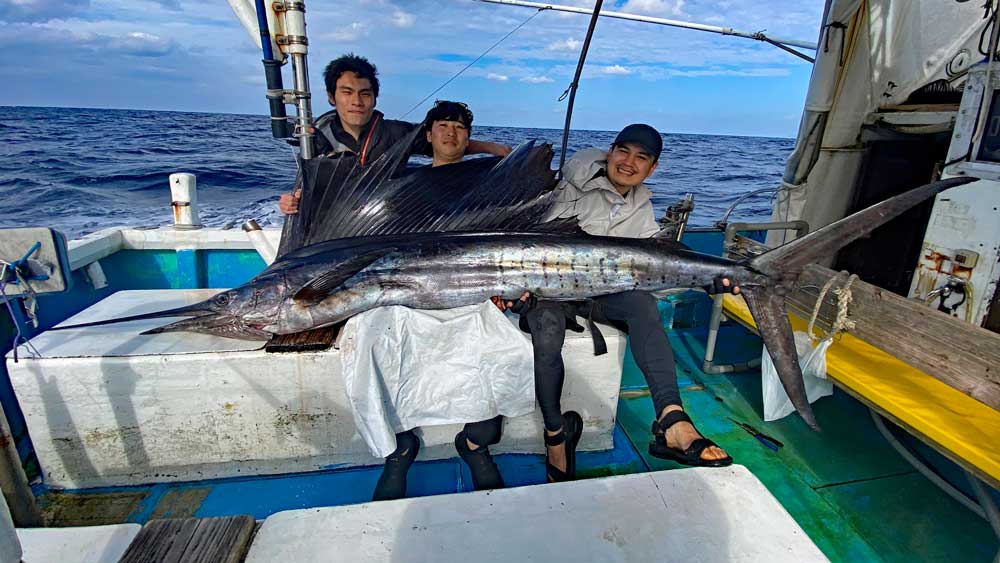 2025年の元旦にトローリングで釣り上げたバショウカジキ(Sailfish)を抱きかかえている3人の男性