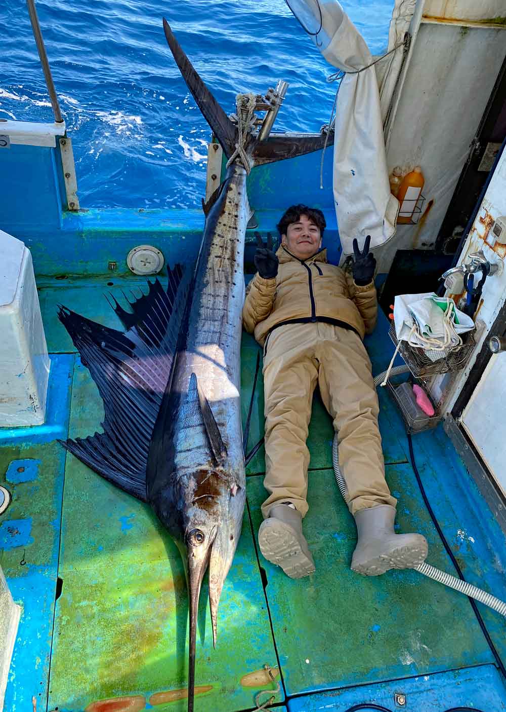 沖縄のトローリングで釣り上げたバショウカジキとピースサインのアングンラー