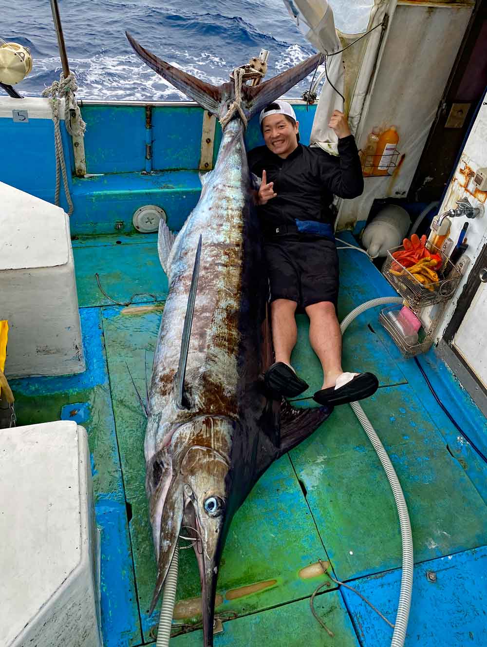 沖縄のトローリングでブルーマーリンを釣り上げた男性