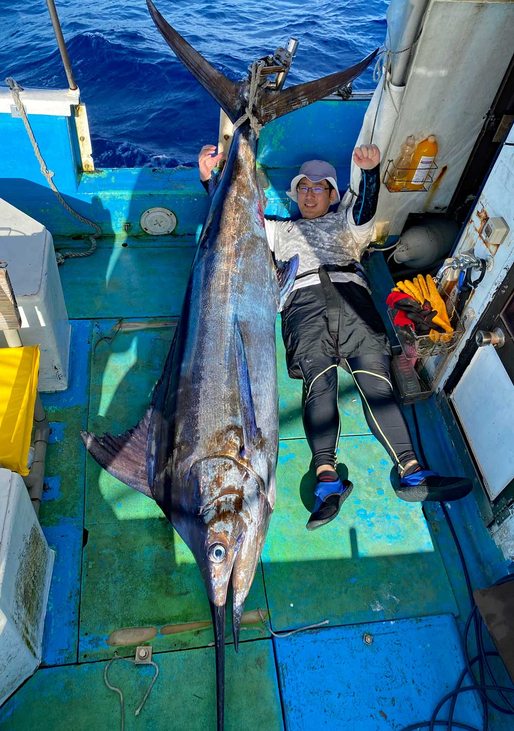 沖縄のトローリングで釣り上げたカジキと喜ぶ男性