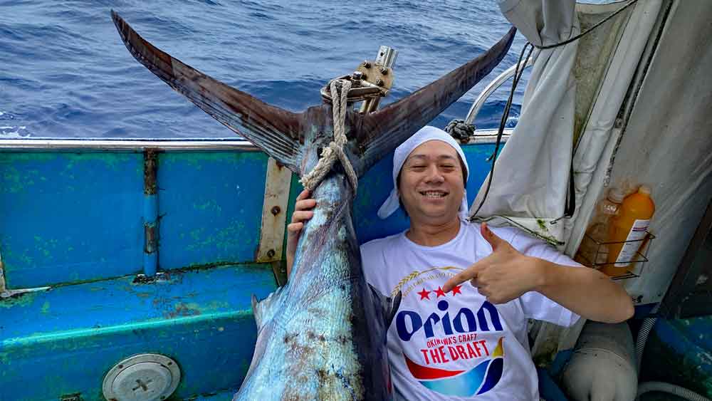 沖縄のトローリングでカジキを釣り上げたオリオンビールシャツの男性