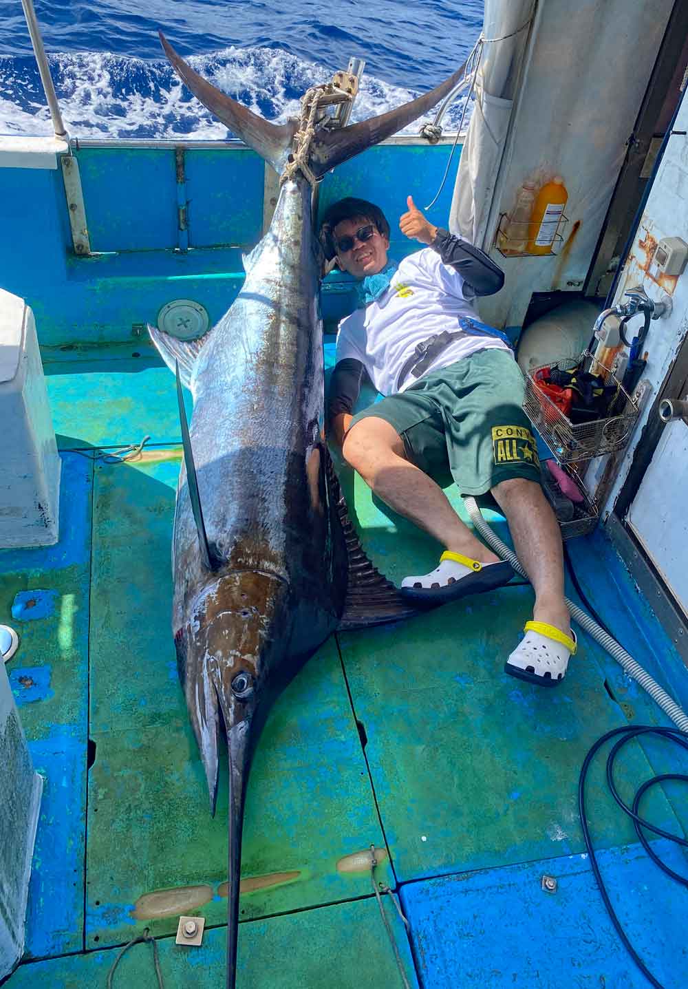 沖縄のトローリングでカジキを釣り上げガッツポーズの男性