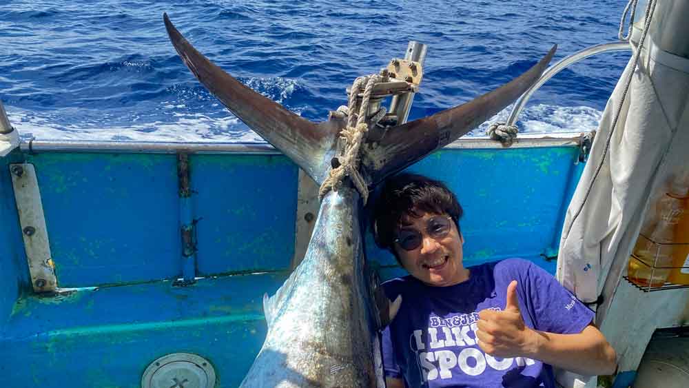 釣り上げたカジキの尾と笑顔の男性