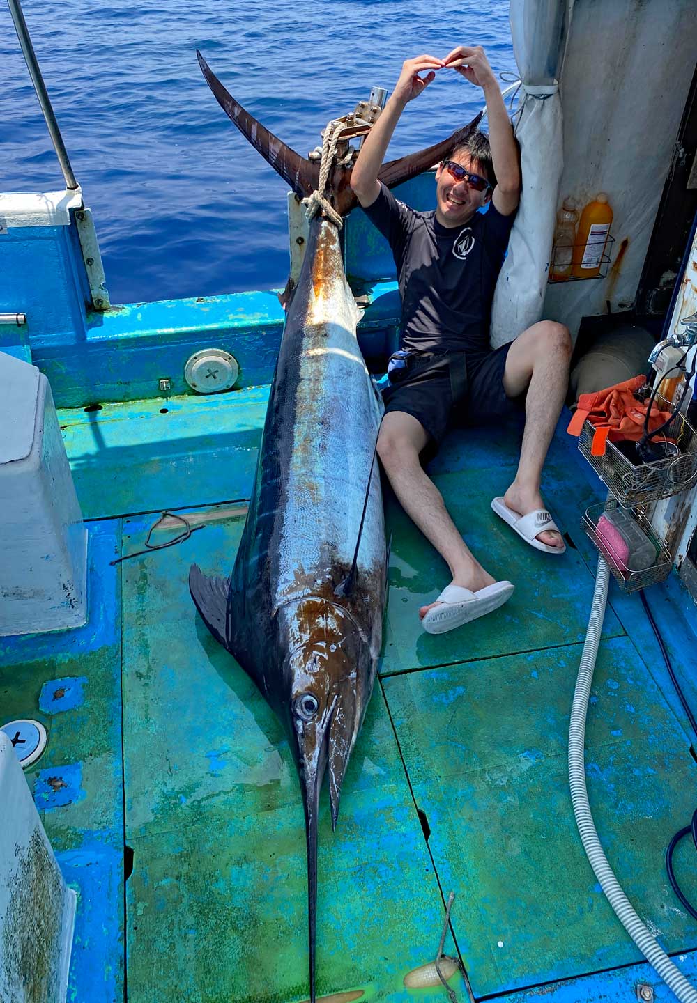 沖縄のトローリングでカジキを釣り喜ぶ男性