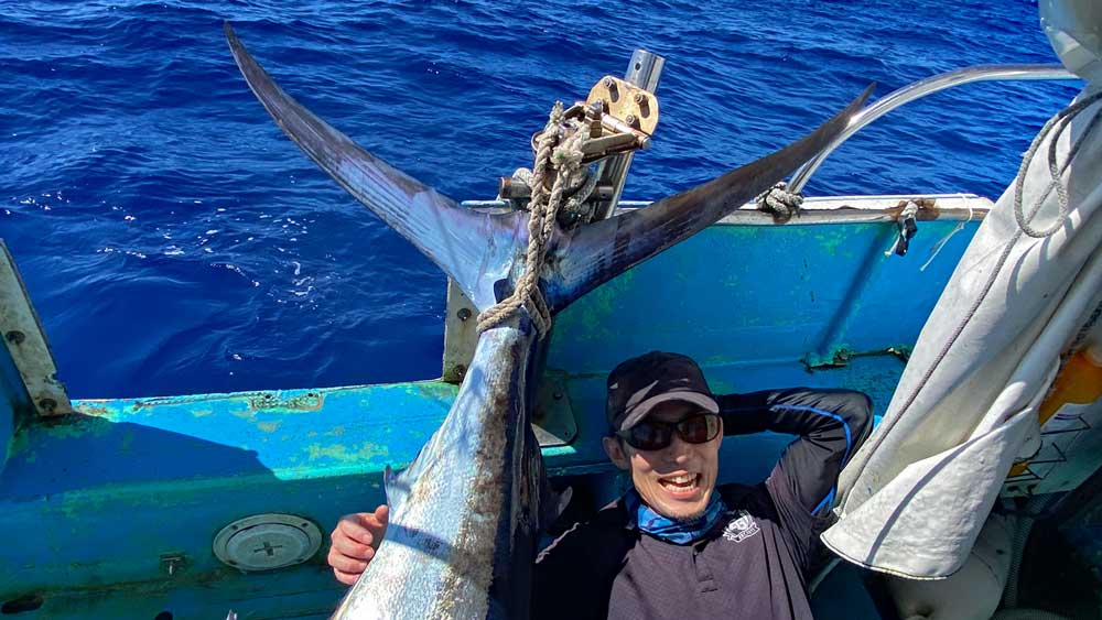 釣り上げたカジキの横になっている笑顔の男性