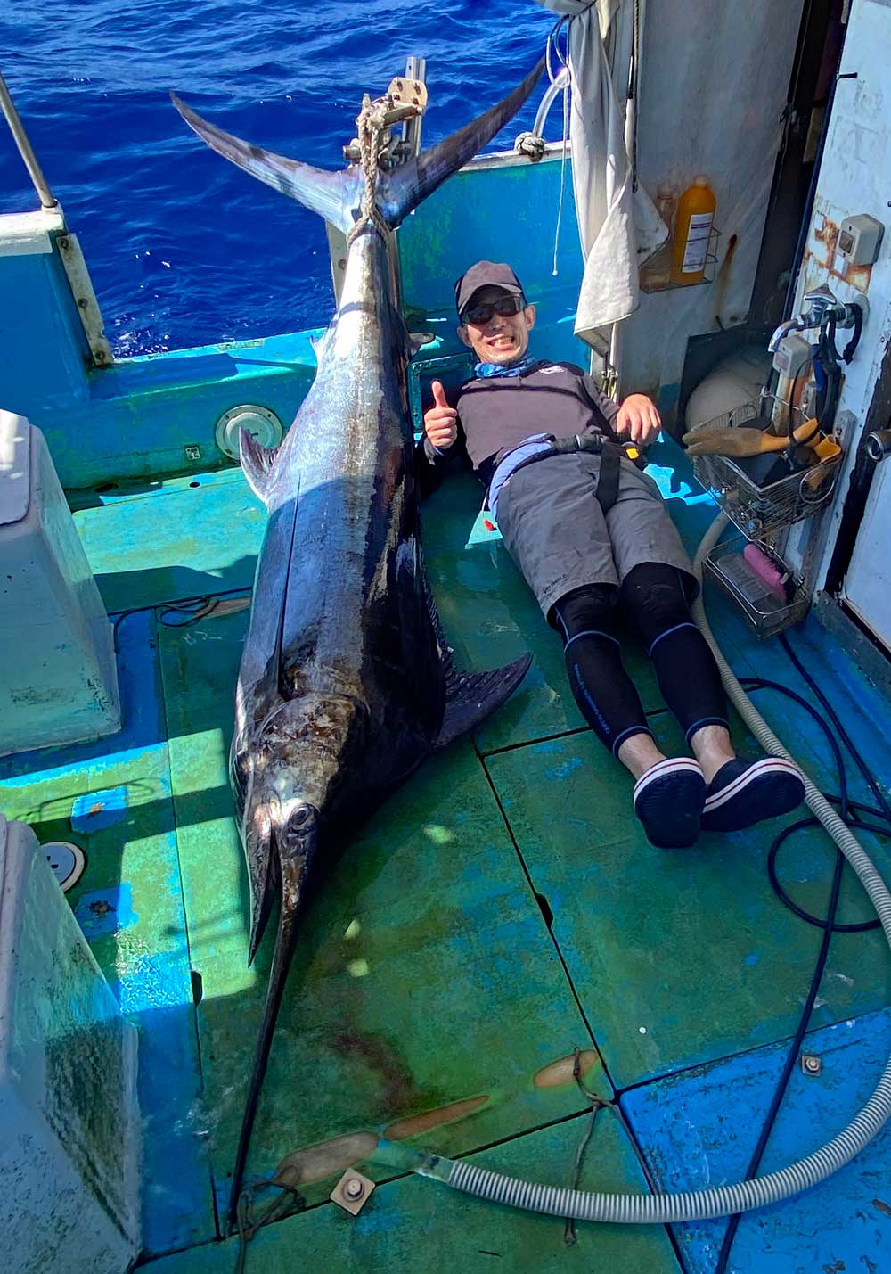 釣り上げたカジキの横になっている男性