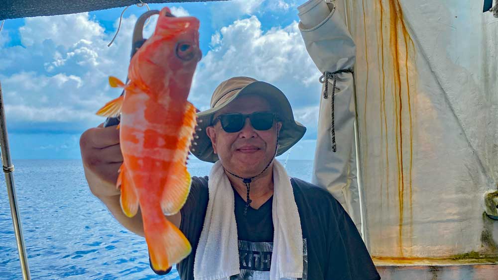沖縄の沖釣りでミーバイを釣り上げた男性