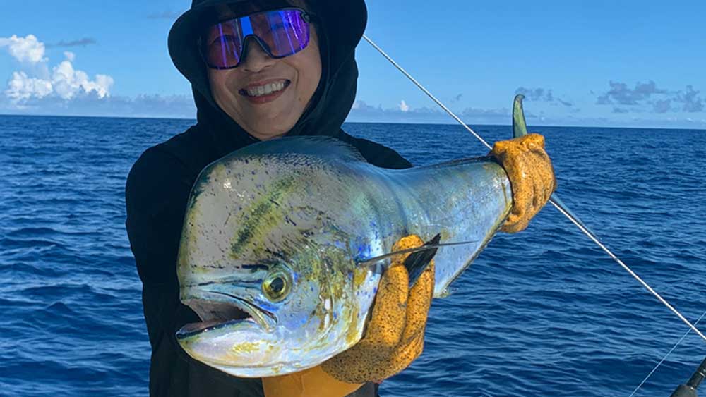 自ら釣り上げたシイラを持ち上げている女性