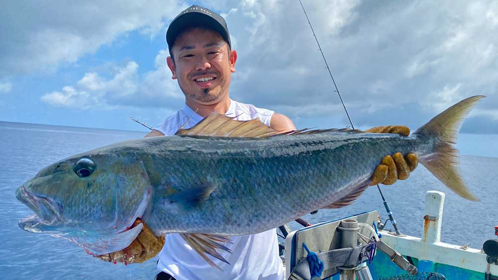 沖縄の沖釣りでアオチビキを釣り上げた男性