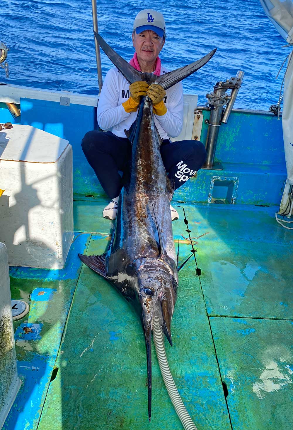 自ら釣り上げたカジキの尾を持ち上げている男性