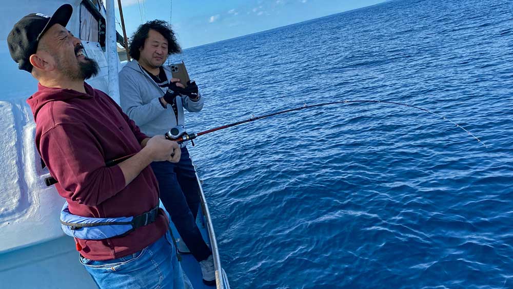 タイラバでタマン(ハマフエフキ)釣りをしている男性と撮影する葉加瀬太郎さん