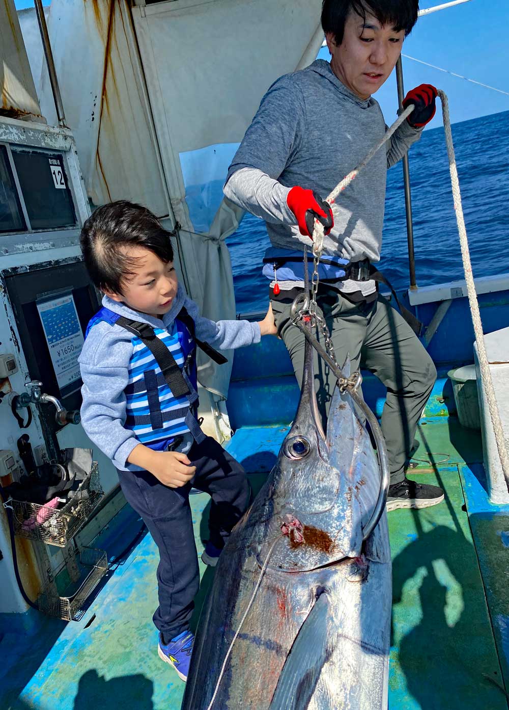 バショウカジキを船に引き上げる親子