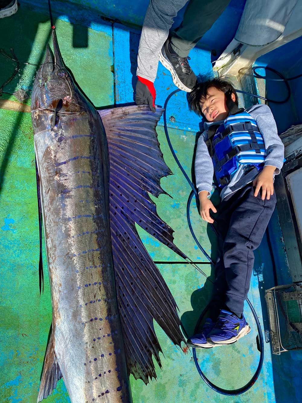 バショウカジキの横に寝ている少年