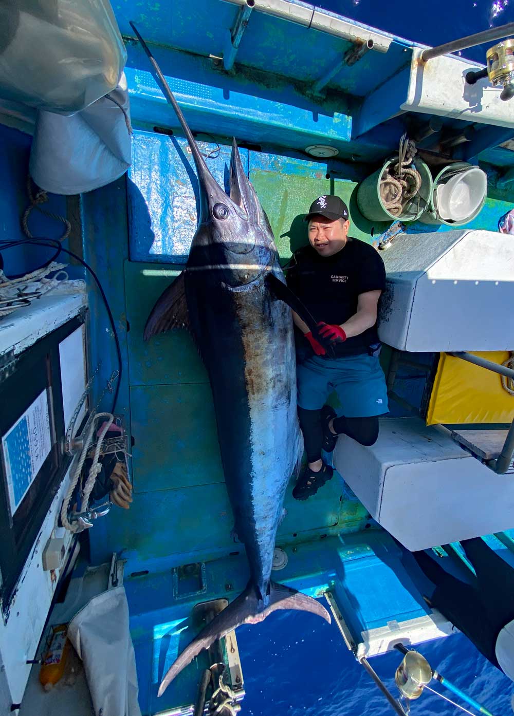 自ら釣り上げた180kgのカジキの横になっている釣り師
