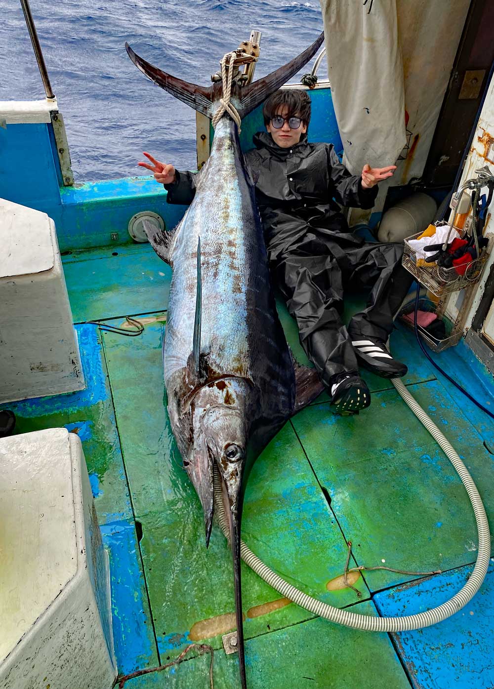船に釣り上げたカジキと20才の男性