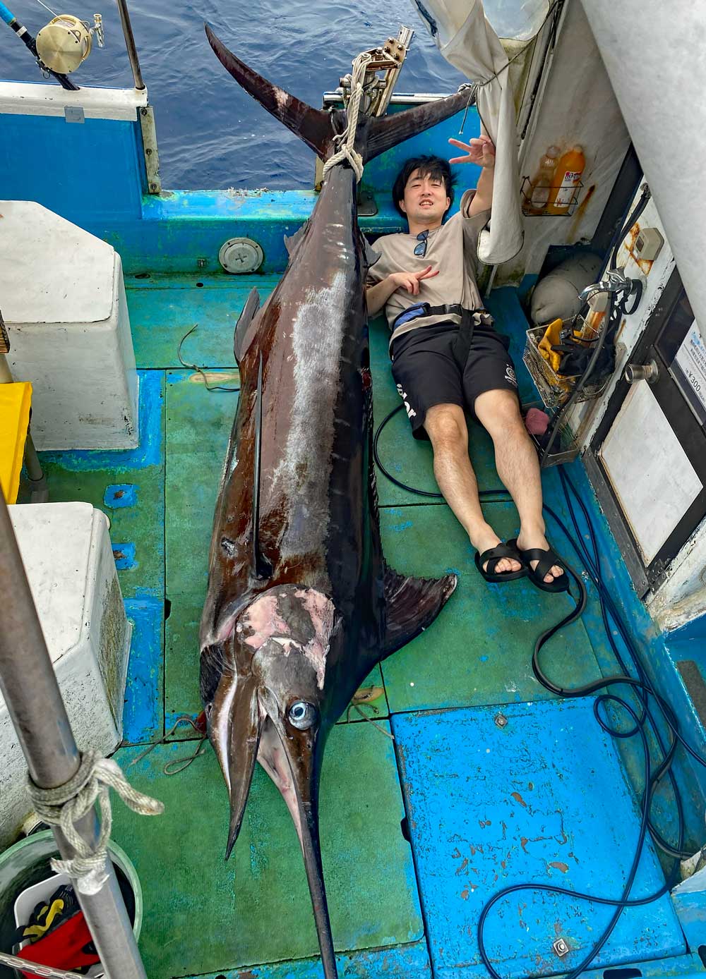 釣り上げた140kgカジキとVサインの男性