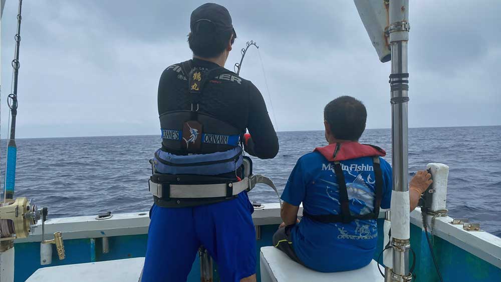 カジキ釣りをしている男性とリモコンで船を操る鶴巻船長